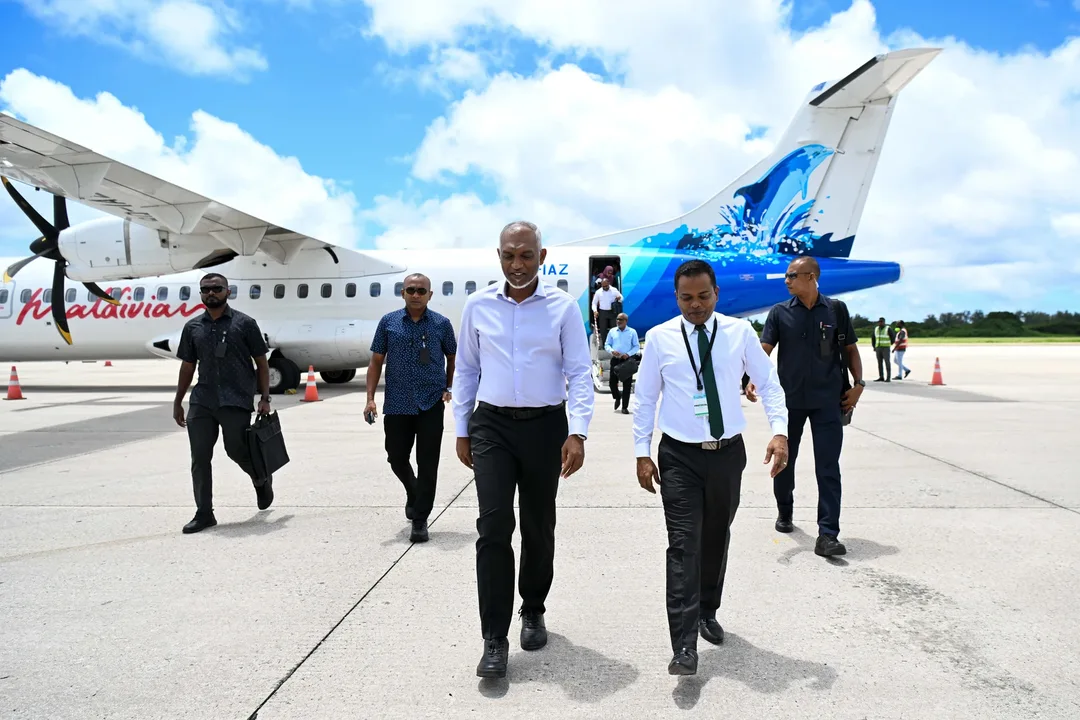 President Mohamed Muizzu walks across the apron at Gan International Airport with officials, a Maldivian ATR turboprop parked behind them.